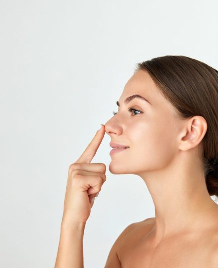 Side view of young attractive woman holding nose isolated on white background. Rhinoplasty surgery. Concept of beauty, plastic surgery, cosmetology, skin care, spa. Ad