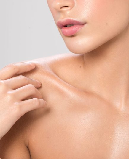 Close up studio shot of a beautiful woman with perfect skin, she applying cream at her shoulder