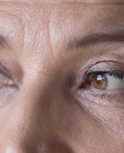 Close up cropped wrinkled front face view of attractive brown-eyed older woman staring into distance looking pensive and thoughtful. Eyes vision check up clinic ad services for older citizen concept