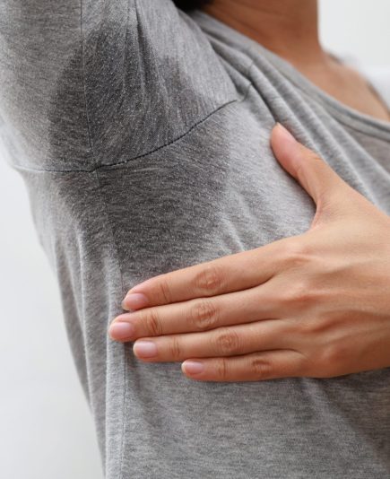 Young asia woman with sweat stain on her clothes against grey background. Healthcare concept.