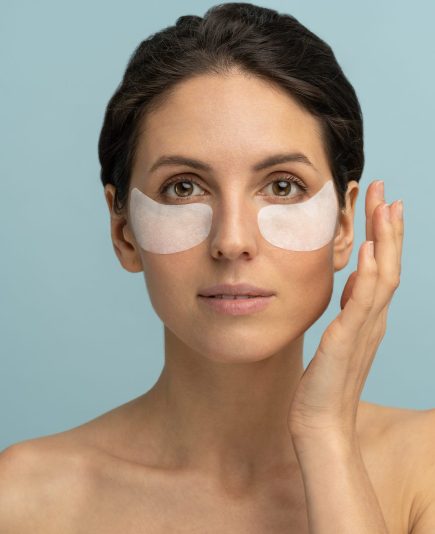 Woman applying hydrogel under-eye recovery patches enriched with collagen, vitamin E, provides intensive hydration and diminishes the signs of aging, helps reduse eye puffiness. Face skincare beauty.